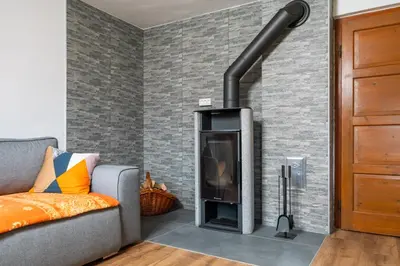 a fireplace in a living room with a gray brick wall at Hiška Nives in Krstenica