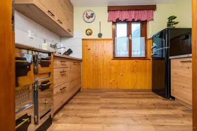 a kitchen with wooden cabinets and a wooden door at Hiška Nives in Krstenica