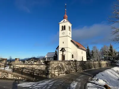 a church with a tower with a clock on it at Hiša p'r Kobalu in Idrija
