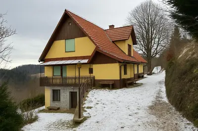 a yellow house with a red roof in the snow at Hiša p'r Kobalu in Idrija
