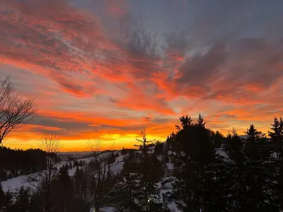 a sunset in the sky with trees and snow at Hiša p'r Kobalu in Idrija