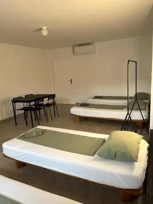 three beds in a room with tables and chairs at Odisej House Tolmin in Tolmin