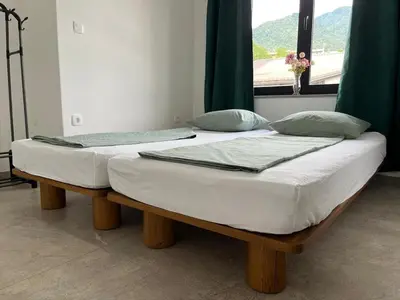 two beds sitting in a room with a window at Odisej House Tolmin in Tolmin