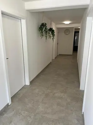 an empty hallway with white walls and tile floors at Odisej House Tolmin in Tolmin