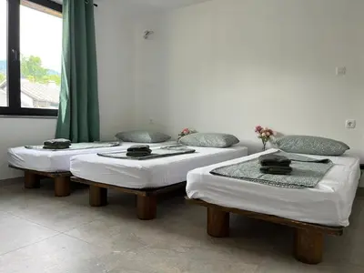 three beds in a room with green curtains at Odisej House Tolmin in Tolmin