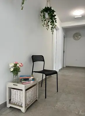 a chair in a room with a table and a clock at Odisej House Tolmin in Tolmin