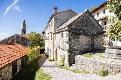 an old stone building with a church in the background at Apartment Valetovi in Štanjel