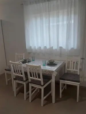 a white table with two chairs and a table with plates and bowls at Pr DOLENC in Petrovče