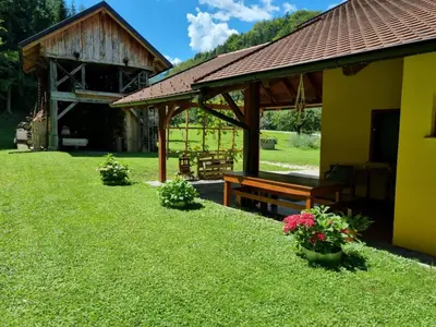 a pavilion with a bench and flowers in a yard at Pr DOLENC in Petrovče