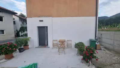 a patio with chairs and a door in a building at Apartma Danica in Kobarid