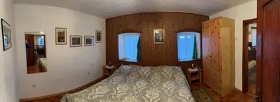 a bedroom with a bed and wooden walls and windows at Hiša p'r Kobalu- in Idrija