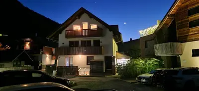 a white house with a balcony and a parking lot at Apartment Brina in Kranjska Gora