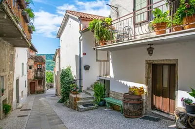 an alley with buildings and a green bench at Hiša Margarita in Ajdovščina