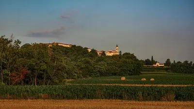 a building on a hill in a field with hay at Hiša Margarita in Ajdovščina