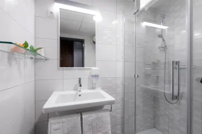 a white bathroom with a sink and a shower at Hotel Florjančkov Hram in Ljubljana