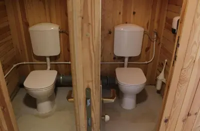 a bathroom with two toilets in a wooden cabin at Outsidersi Campsite