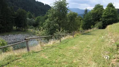 a fence next to a river next to a field at Outsidersi Campsite