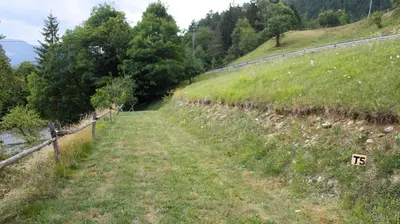 a field of grass with a fence on a hill at Outsidersi Campsite