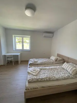 two beds in a room with a desk and a window at VP sobe in Ilirska Bistrica