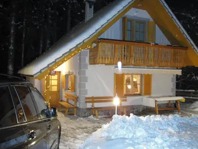 a house in the snow with a car parked in front at Holiday House Kaja in Mojstrana