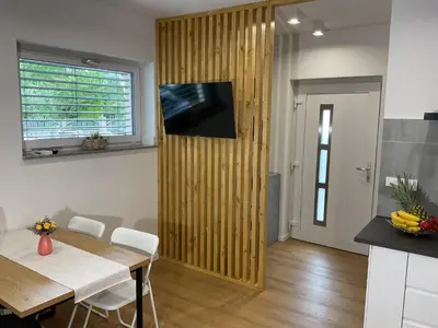 a living room with a table and a television on a wall at Apartma Tomy in Domžale