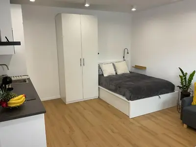 a white room with a bed and a kitchen at Apartma Tomy in Domžale