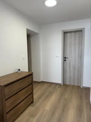 an empty room with a wooden dresser and a door at Apartma Center Ljutomer in Ljutomer
