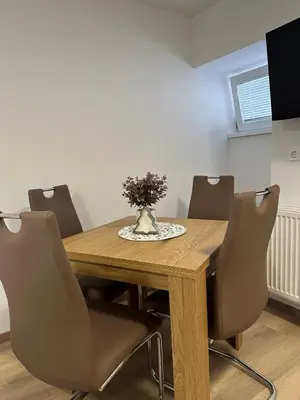 a dining room table with chairs and a vase of flowers at Apartma Center Ljutomer in Ljutomer