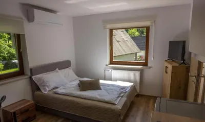 a small bedroom with a bed and a window at Stara ribogojnica & Pohorska postrv in Ruše