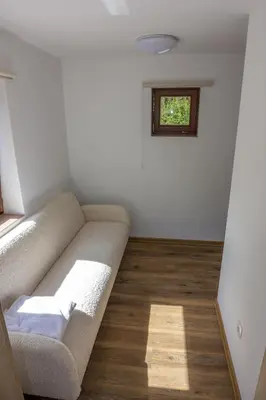 a living room with a couch and a window at Stara ribogojnica & Pohorska postrv in Ruše