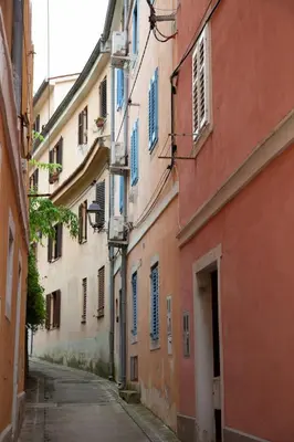 an alley with orange buildings with blue shutters at Rosa di Pirano con Terrazza in Rove