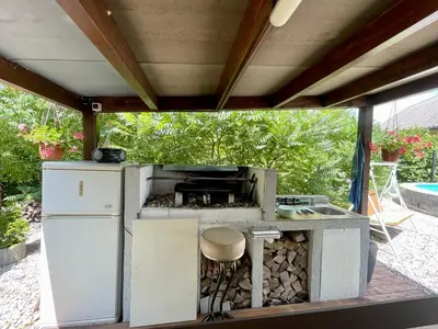 an outdoor kitchen with a stove and a refrigerator at Quiet Forest Retreat with Pool in Borovnica