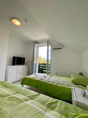 two beds in a white room with a window at Quiet Forest Retreat with Pool in Borovnica