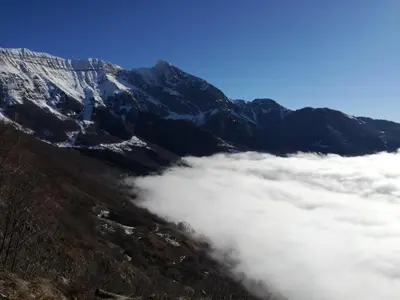 a group of mountains with clouds in front of them at Apartma ARNEJ in Kobarid