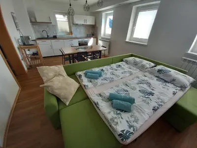 a green couch in a living room with a kitchen at Apartma ARNEJ in Kobarid