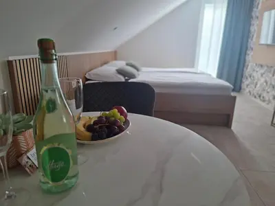 a bottle of wine and a bowl of fruit on a table at APARTMA BriGITA in Gorica pri Slivnici