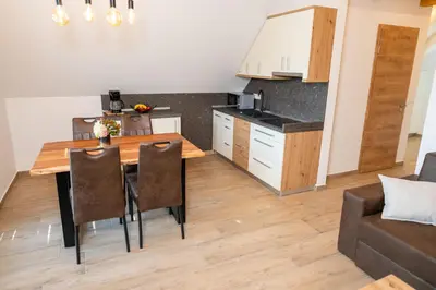 a kitchen and living room with a wooden table and chairs at Apartma Urška in Bohinj