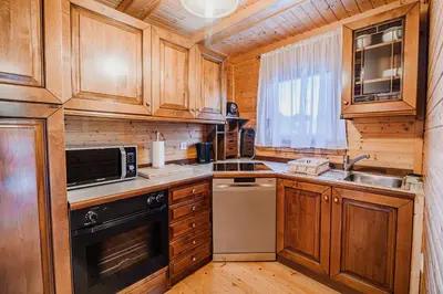 a kitchen with wooden cabinets and a sink and a stove at Log Cabin Vista View with Seasonal Hot Tub in Bizeljsko