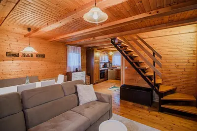 a living room with a couch and a staircase at Log Cabin Vista View with Seasonal Hot Tub in Bizeljsko