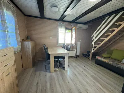 a room with a table and chairs and stairs at Ferienhaus Čatež Holzhaus an der Therme Čatež in Brežice
