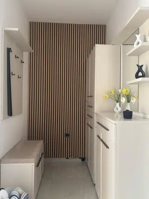a kitchen with white cabinets and a wooden wall at Modern Stay House Ptuj in Ptuj
