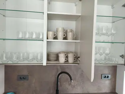 a kitchen with white cabinets with glasses and a sink at Modern Stay House Ptuj in Ptuj