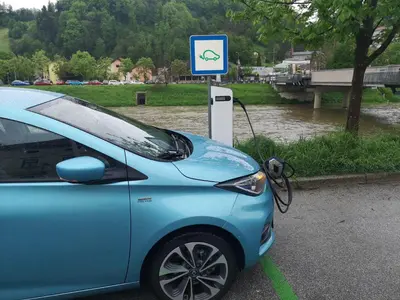 a blue car parked in a parking lot next to a sign at Hiša Elsbacher Laško in Laško