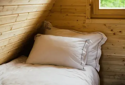 a bed in a log cabin with two pillows at Lipa Plac in Postojna