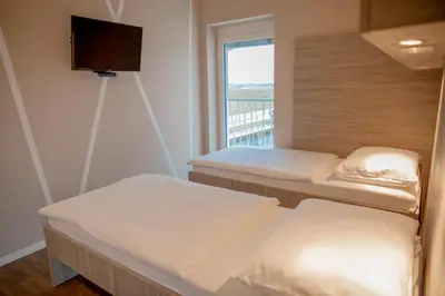 a room with three beds and a window at Garni Hotel Krško in Leskovec pri Krškem