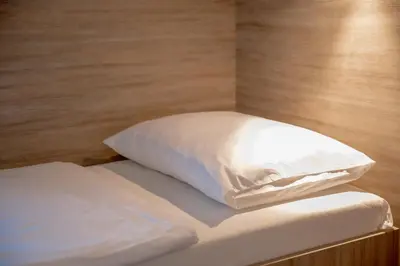 a bed with white sheets and a pillow on it at Garni Hotel Krško in Leskovec pri Krškem