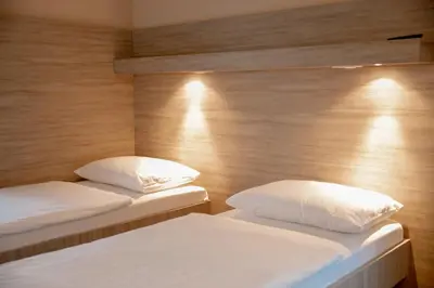 two beds in a room with wooden walls at Garni Hotel Krško in Leskovec pri Krškem