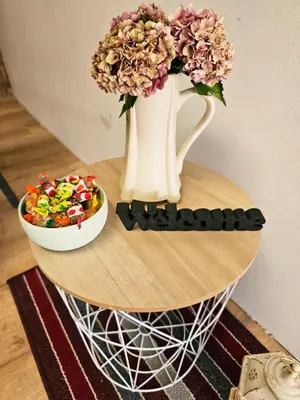 a table with a vase with flowers and a bowl of candy at Hostel pod gradom in Celje