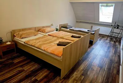 two beds in a bedroom with wooden floors at Hostel pod gradom in Celje