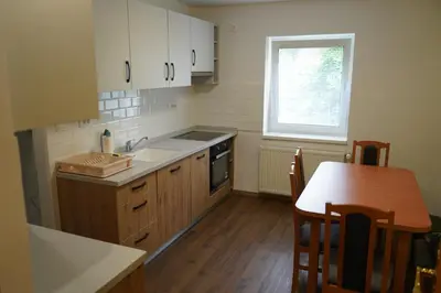 a kitchen with white cabinets and a table and a window at Apartma Mlinca 1 in Mojstrana